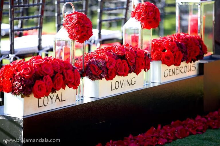 Bright red roses arranged in white planters with special wedding captions