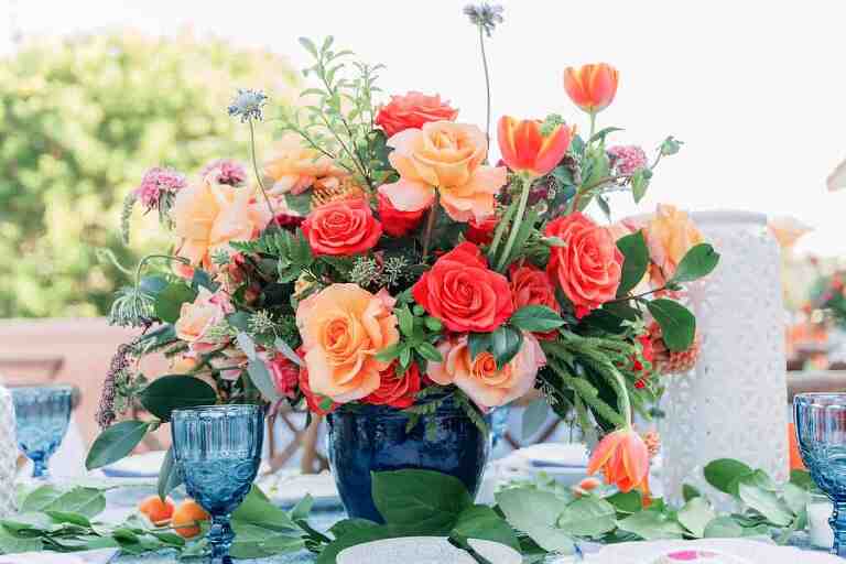 A table with a vase of beautifully arranged colorful flowers on it