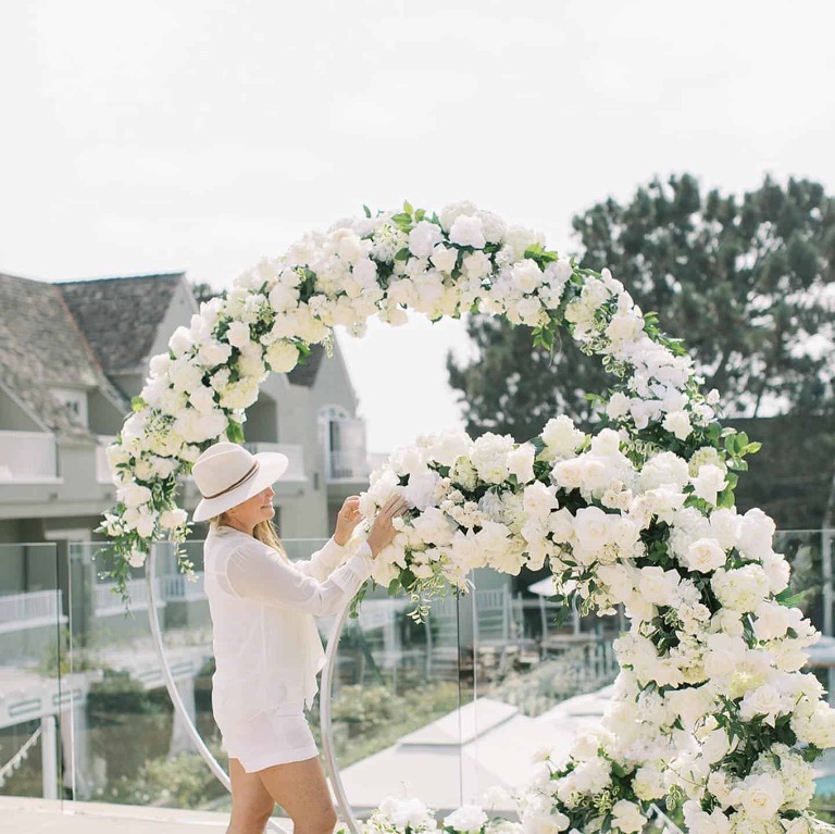 A woman arranging the white flower setup for a wedding